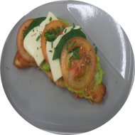 Frühstück in der Cafete: 'Smashed Croissant' - Geröstetes Buttercroissant mit hausgemachtem Avocadotatar dazu Tomate, Mozzarella und Basilikum (2,3,15,19,81,83) dazu ein Heißgetränk 0,2l